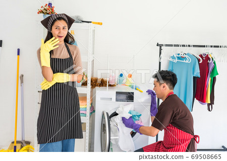 Lazy woman laugh while man laundry  alone 69508665