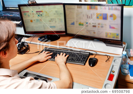 A young man works at a computer, sitting at table, distance learning, self-education in quarantine. A young man works at a computer, sitting at table, distance learning, self-education in quarantine. 69508798