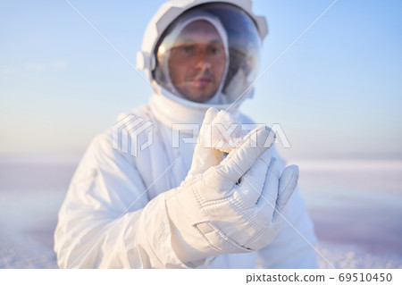 Close up shot of an astronaut in holding mineral crystal Close up shot of an astronaut in holding mineral crystal 69510450