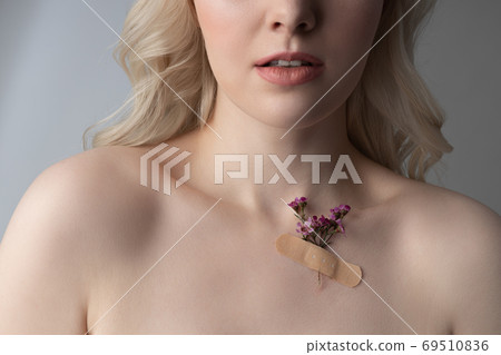 Young woman with flower on her skin standing against gray background 69510836