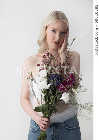 Charming young woman with flowers standing against white background Charming young woman with flowers standing against white background 69510892