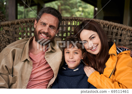 Happy family sitting on wicker chair outdoors 69511461