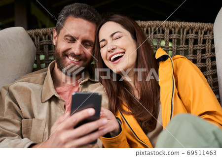 Happy young couple using modern smartphone outdoors 69511463