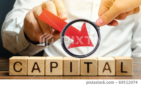 Wooden blocks with the word Capital and arrow down in the hands of a businessman. The concept of the fall in the level of authorized capital. Economic recession and crisis. Drop in return on equity Wooden blocks with the word Capital and arrow down in the hands of a businessman. The concept of the fall in the level of authorized capital. Economic recession and crisis. Drop in return on equity 69512074