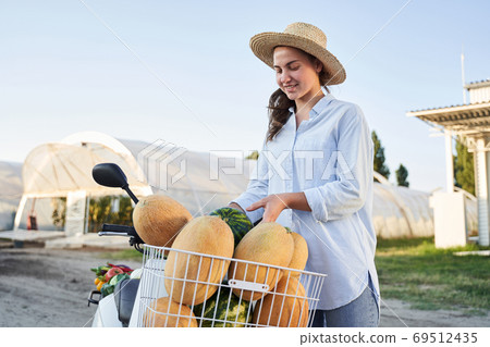 Woman with scooter and melons in basket Woman with scooter and melons in basket 69512435