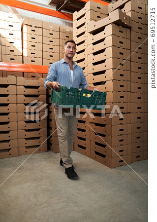 Attractive man with box in warehouse 69512715