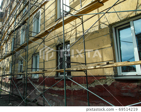 scaffolding stands along the wall of a building preparing for repair scaffolding stands along the wall of a building preparing for repair 69514219