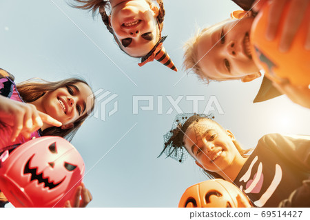 Happy kids in Halloween costumes against sky. 69514427