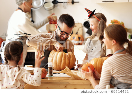 Multi generational family making jack o lantern. 69514431