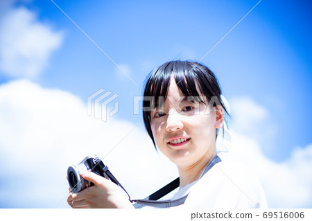 拿著照相機的一個少婦反對藍天 拿著照相機的一個少婦反對藍天 69516006