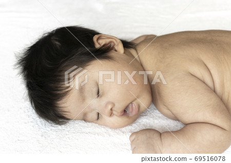 Face of a two-month-old naked baby lying down 69516078