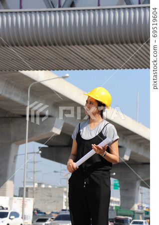 Female civil engineer or architect with yellow helmet, standing 69519604
