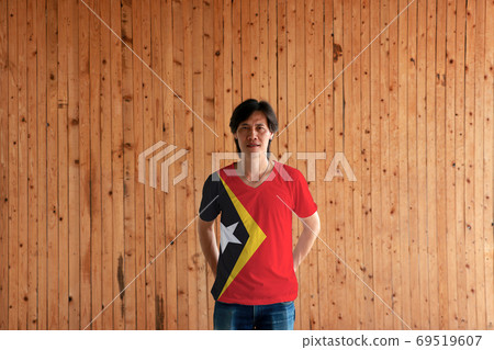 Man wearing Timor Leste flag color and standing with crossed beh Man wearing Timor Leste flag color and standing with crossed beh 69519607