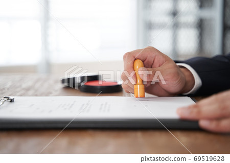 Japanese male businessman stamping a corporate seal on documents Japanese male businessman stamping a corporate seal on documents 69519628