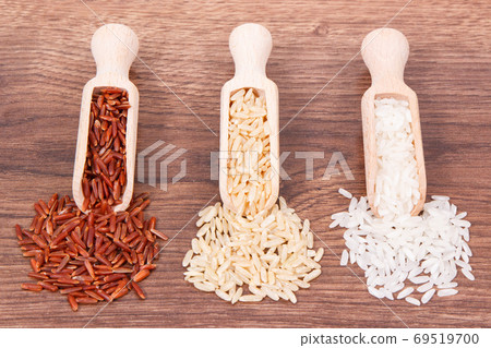 Red, brown and white rice with wooden scoop on rustic board Red, brown and white rice with wooden scoop on rustic board 69519700