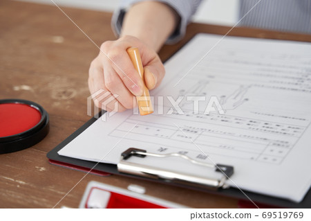 Hands of a Japanese woman who stamps a personal seal on a document Hands of a Japanese woman who stamps a personal seal on a document 69519769