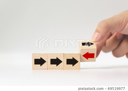 Hand flip over wooden cube block with red arrow facing the opposite direction black arrows 69519977