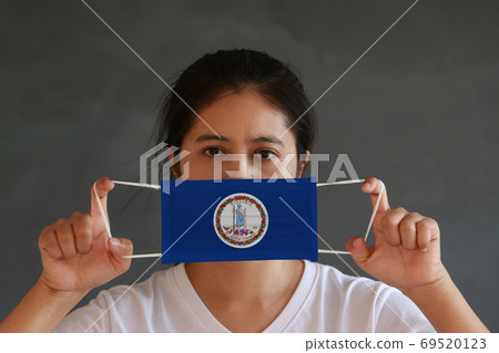 A woman and hygienic mask with Virginia flag pattern in her hand A woman and hygienic mask with Virginia flag pattern in her hand 69520123