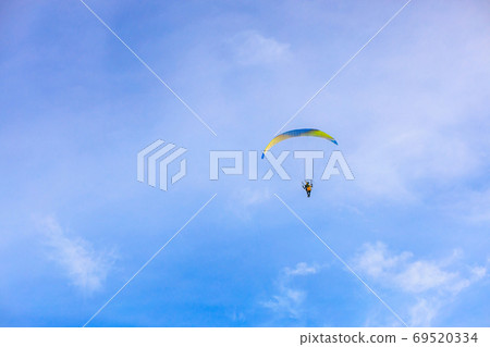A flying paramotor on a vibrant sky with cloud. A flying paramotor on a vibrant sky with cloud. 69520334