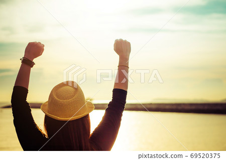 Silhouette of young woman enjoying victory and rise the hand and scream 69520375