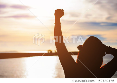 Silhouette of young woman enjoying victory and rise the hand and scream 69520376