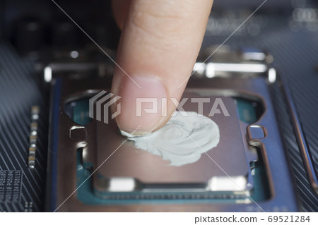 Applying thermal paste with finger in CPU on motherboard Applying thermal paste with finger in CPU on motherboard 69521284