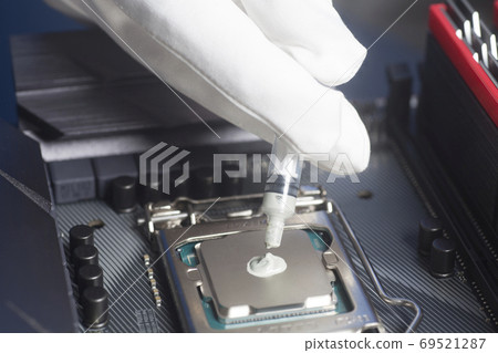 Hands wearing White Gloves with syringe applying thermal paste on the CPU processor on motherboard Hands wearing White Gloves with syringe applying thermal paste on the CPU processor on motherboard 69521287