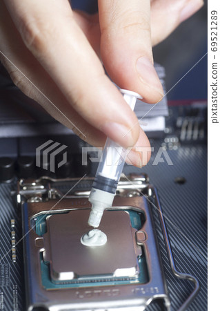 Hand with syringe applying thermal paste on the CPU processor on motherboard Hand with syringe applying thermal paste on the CPU processor on motherboard 69521289