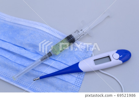 Syringe, protective mask and electronic thermometer on a grey background.Vaccination against the virus. Syringe, protective mask and electronic thermometer on a grey background.Vaccination against the virus. 69521986