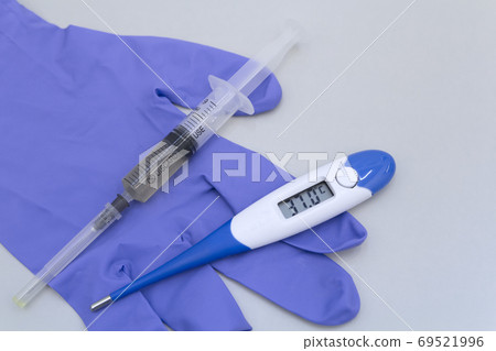 Syringe, glove and electronic thermometer on a grey background. Syringe, glove and electronic thermometer on a grey background. 69521996