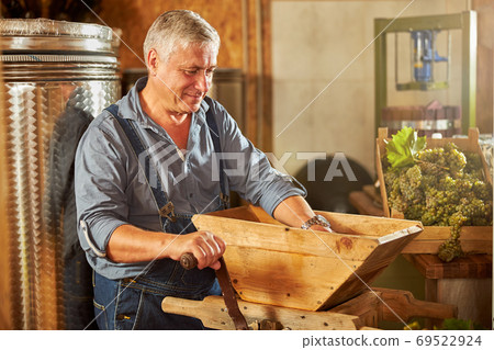 Contented winery worker operating a grape crusher 69522924