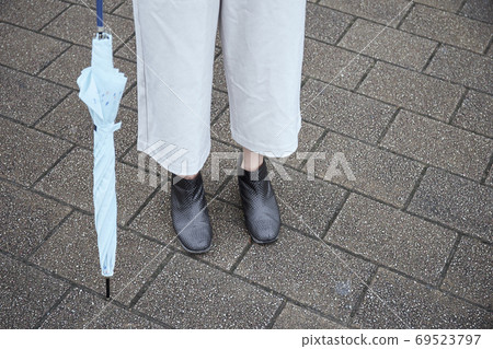 Women's feet with rain boots and an umbrella Women's feet with rain boots and an umbrella 69523797