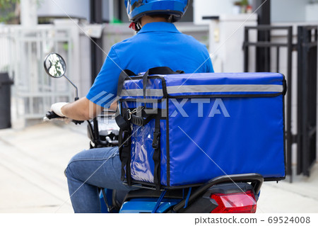 Delivery man wearing blue uniform riding motorcycle and delivery box. Delivery man wearing blue uniform riding motorcycle and delivery box. 69524008