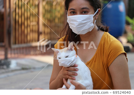 Masked Asian woman and her cat prevent germs.  69524040