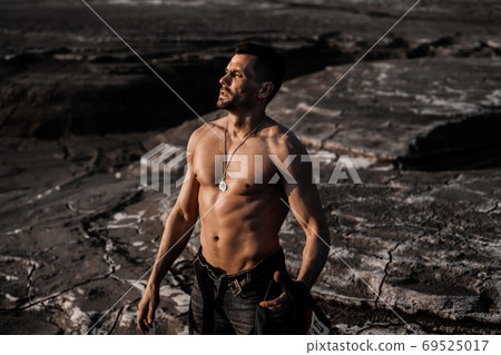 Attractive tanned man on the black sand Attractive tanned man on the black sand 69525017