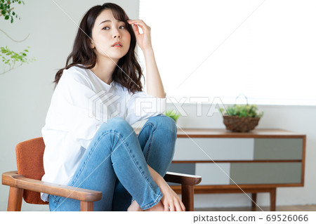 Young woman sitting on a chair in the living room Young woman sitting on a chair in the living room 69526066