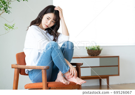 Young woman sitting on a chair in the living room Young woman sitting on a chair in the living room 69526067