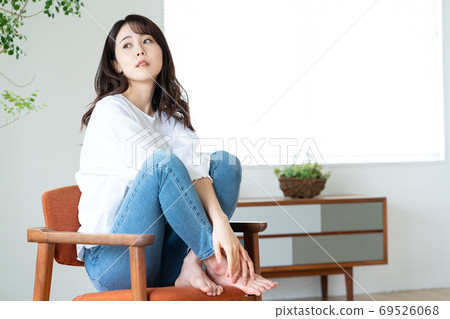 Young woman sitting on a chair in the living room Young woman sitting on a chair in the living room 69526068