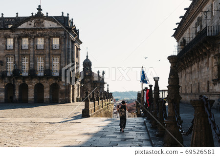 Unidentified woman is walking alone by empty Obradoiro Square in Santiago 69526581