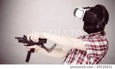 Gamer man wearing VR holding gun Gamer man wearing VR holding gun 69526831