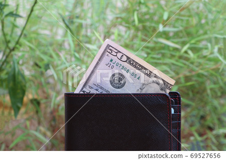 Banknote money fifty US dollar and black wallet on green nature background. Banknote money fifty US dollar and black wallet on green nature background. 69527656