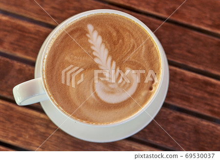 Drawing on the coffee foam. White saucer and cup with coffee, to 69530037
