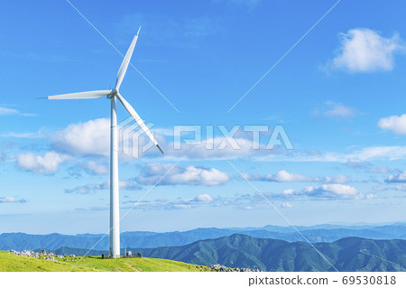 A wind power plant towering over a hill (image of renewable energy) A wind power plant towering over a hill (image of renewable energy) 69530818