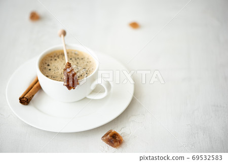 a cup of black coffee with cinnamon and caramelized sugar on a stick a cup of black coffee with cinnamon and caramelized sugar on a stick 69532583