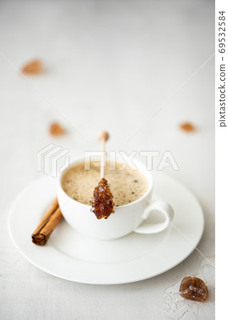 a cup of black coffee with cinnamon and caramelized sugar on a stick a cup of black coffee with cinnamon and caramelized sugar on a stick 69532584