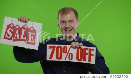 Cheerful man showing Sale word and showing Up To 70 percent Off inscription. Black Friday concept Cheerful man showing Sale word and showing Up To 70 percent Off inscription. Black Friday concept 69532700