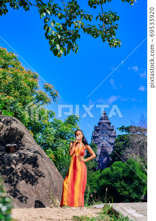 Beautiful woman in colorful dress posing near the rock with old Beautiful woman in colorful dress posing near the rock with old 69533920