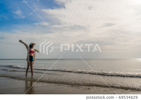 freedom woman in bikini walking with arms raised on sea beach 69534829