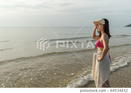cheerful woman in bikini standing at sea beach 69534832