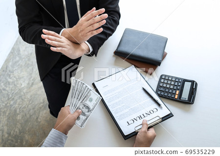 Businessman refusing receive bribe money of their Businessman refusing receive bribe money of their 69535229